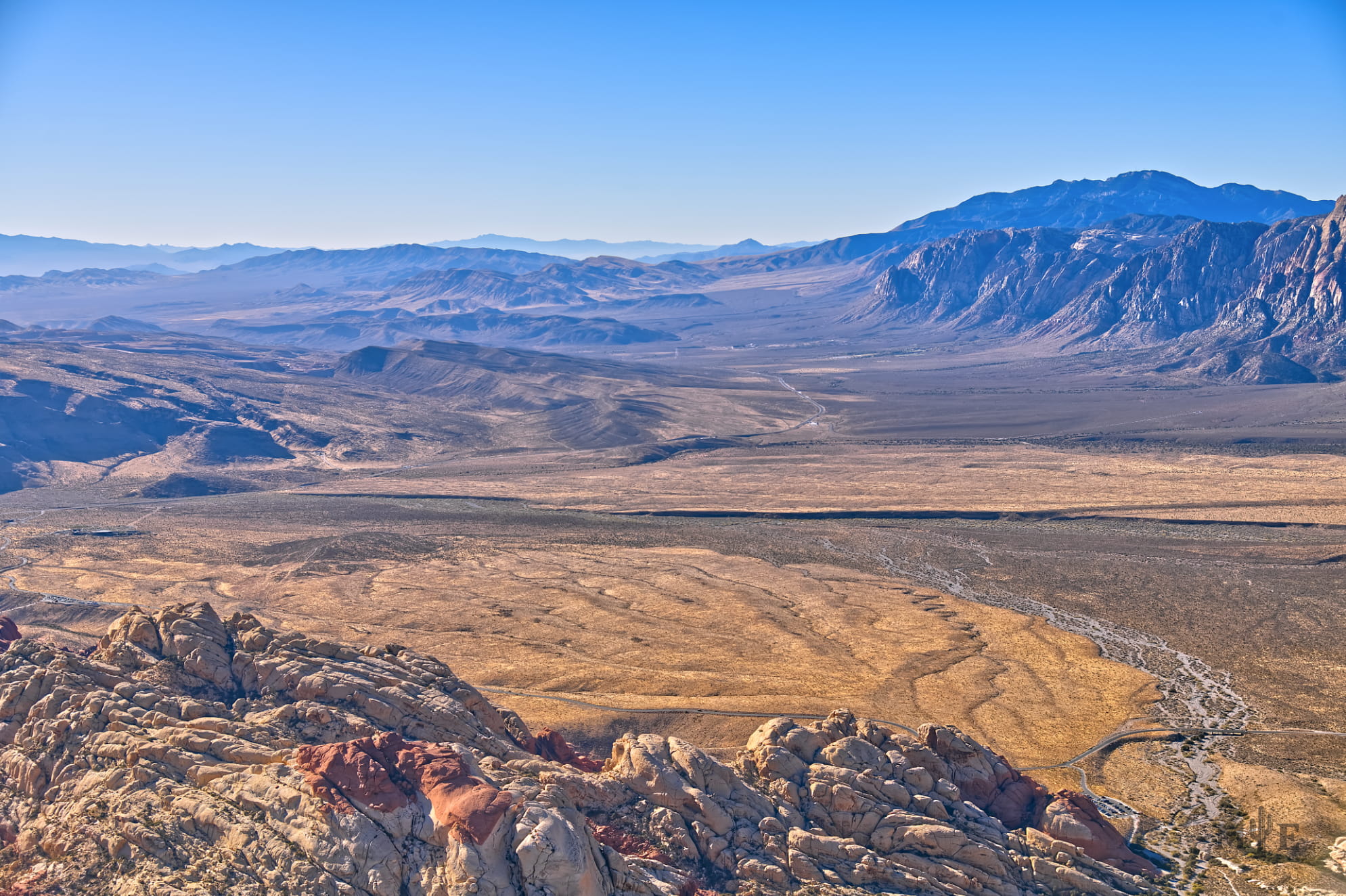 Sandstone mountains and a desert valley under a blue sky. Indicative of aerial photography.