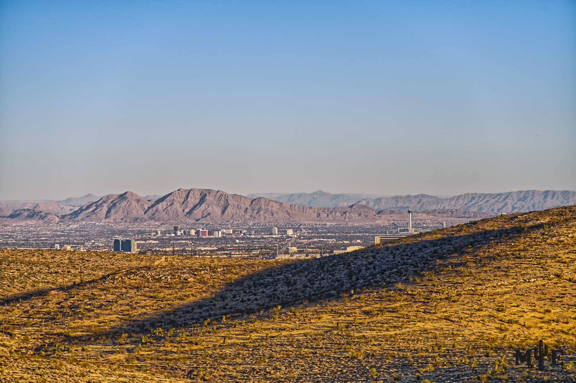 Rolling desert, shadowed terrain and detailed mountains late afternoon with the City of Las Vegas gently sitting between.