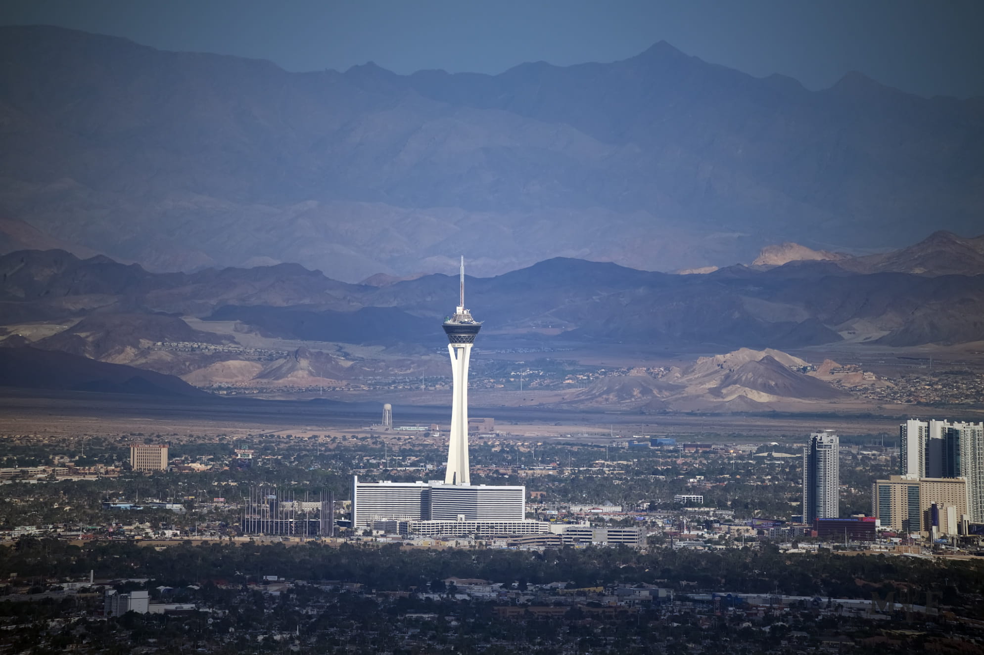 Prominent capture of the stratosphere making it look like an ivory tower among layered mountains and a dark Las Vegas valley.