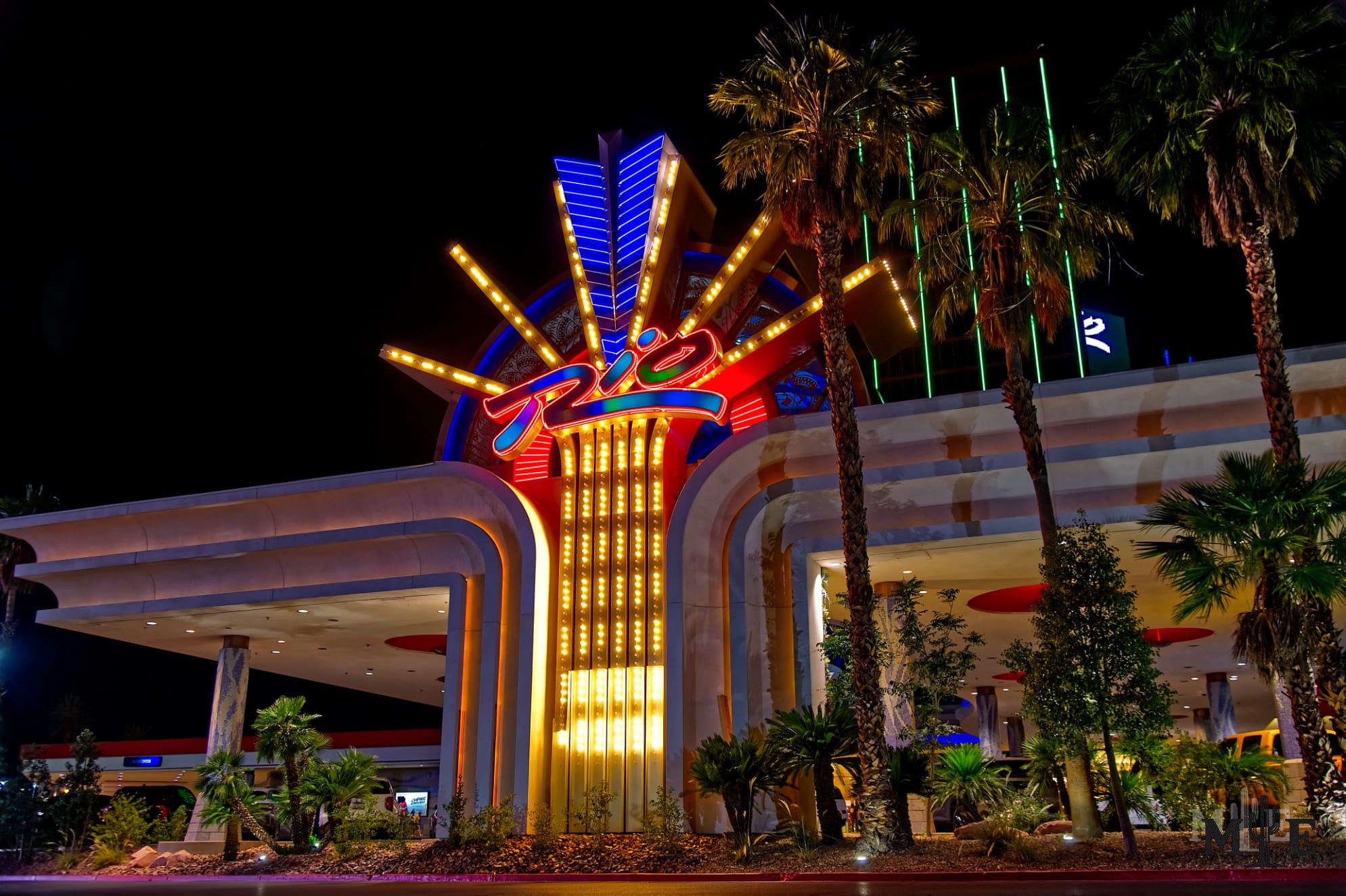The Rio Las Vegas entrance glowing with vivid neon beneath a black night sky.