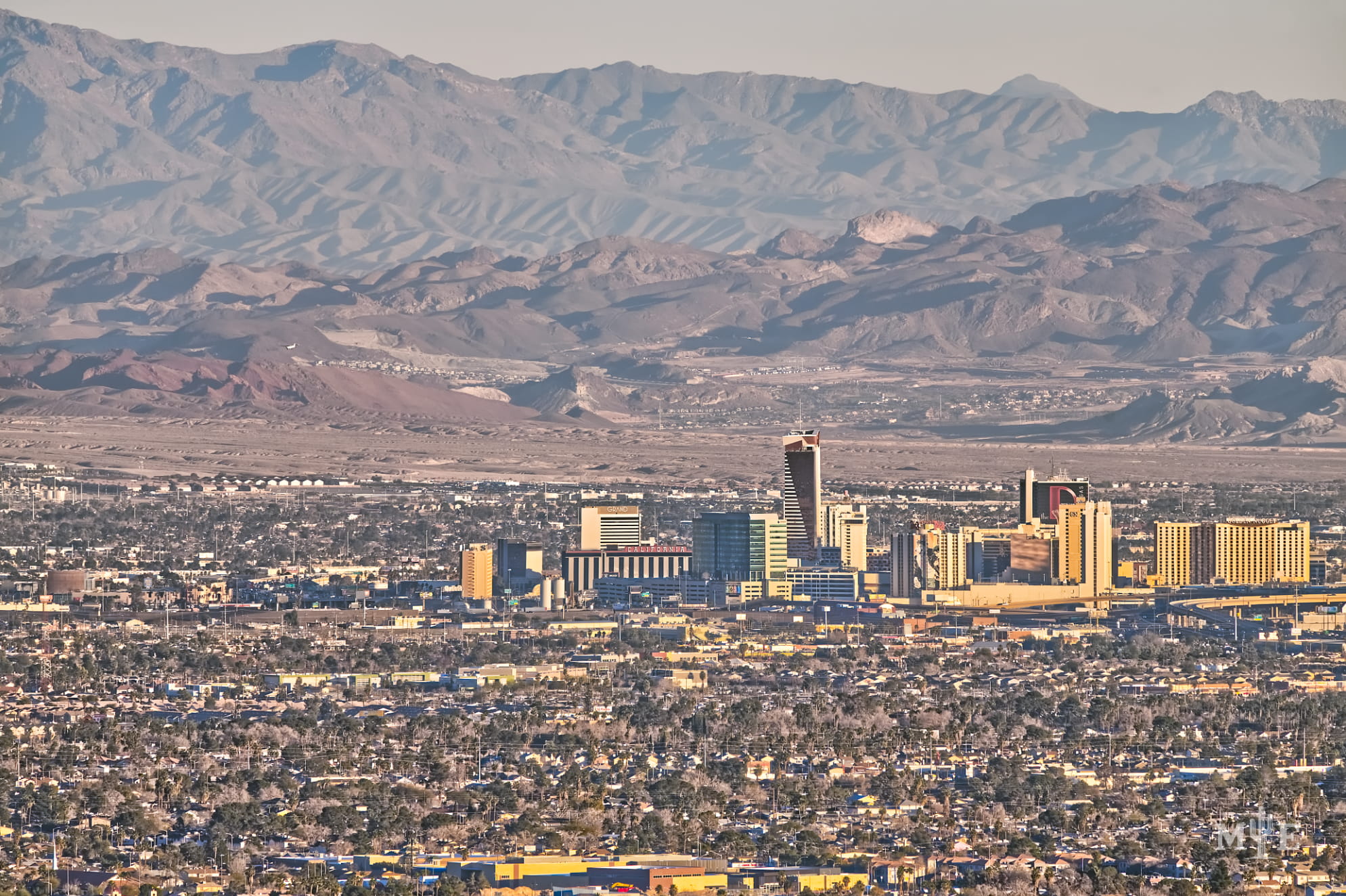 Busy metropolitan photo of layered mountains in Clark County, the dense Las Vegas valley, and Fremont St hotels.
