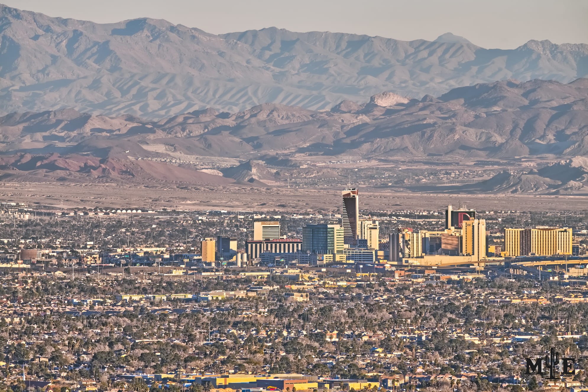 Busy metropolitan photo of layered mountains in Clark County, the dense Las Vegas valley, and Fremont St hotels.