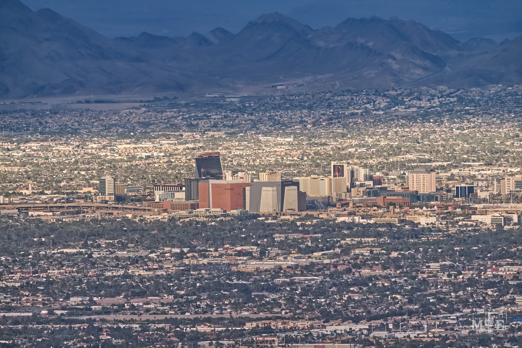 Telephoto photography of downtown Las Vegas front and center, surrounding metropolitan area and mountainous background.