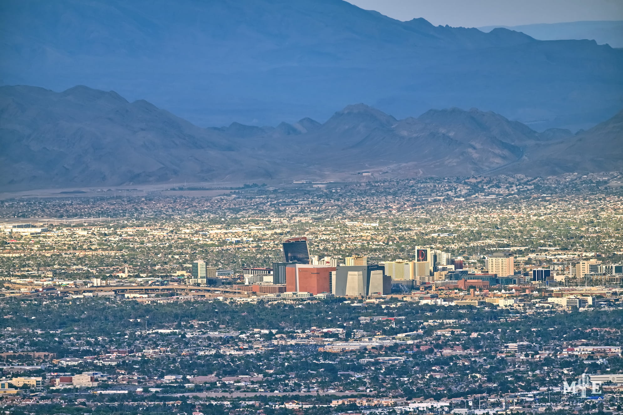 Telephoto photography with a dense collection of hotels in downtown Las Vegas, layered mountains and surrounding city.
