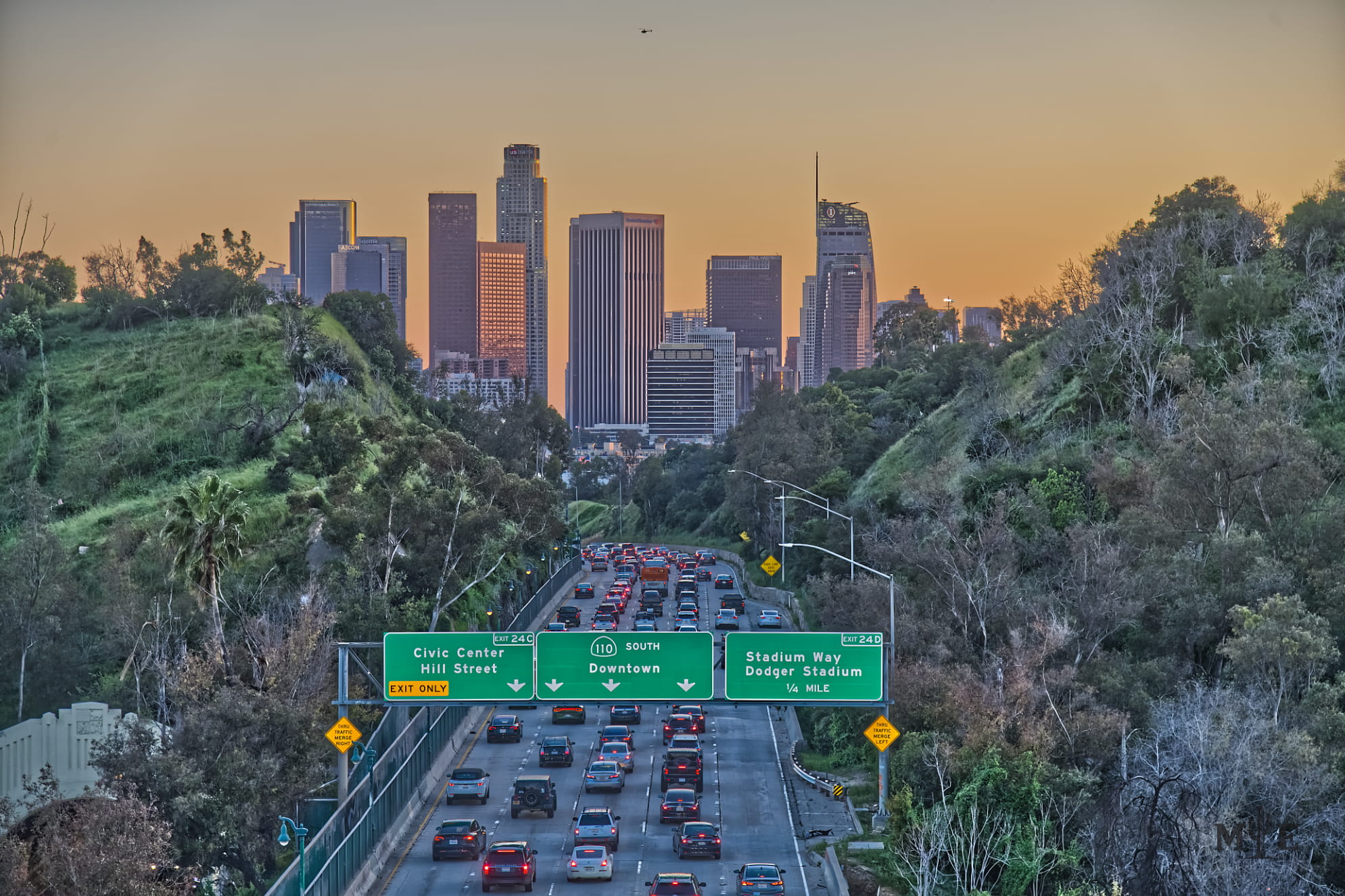 Striking image of Downtown Los Angeles with slow moving traffic cutting through ravine on the freeway with downtown signage.