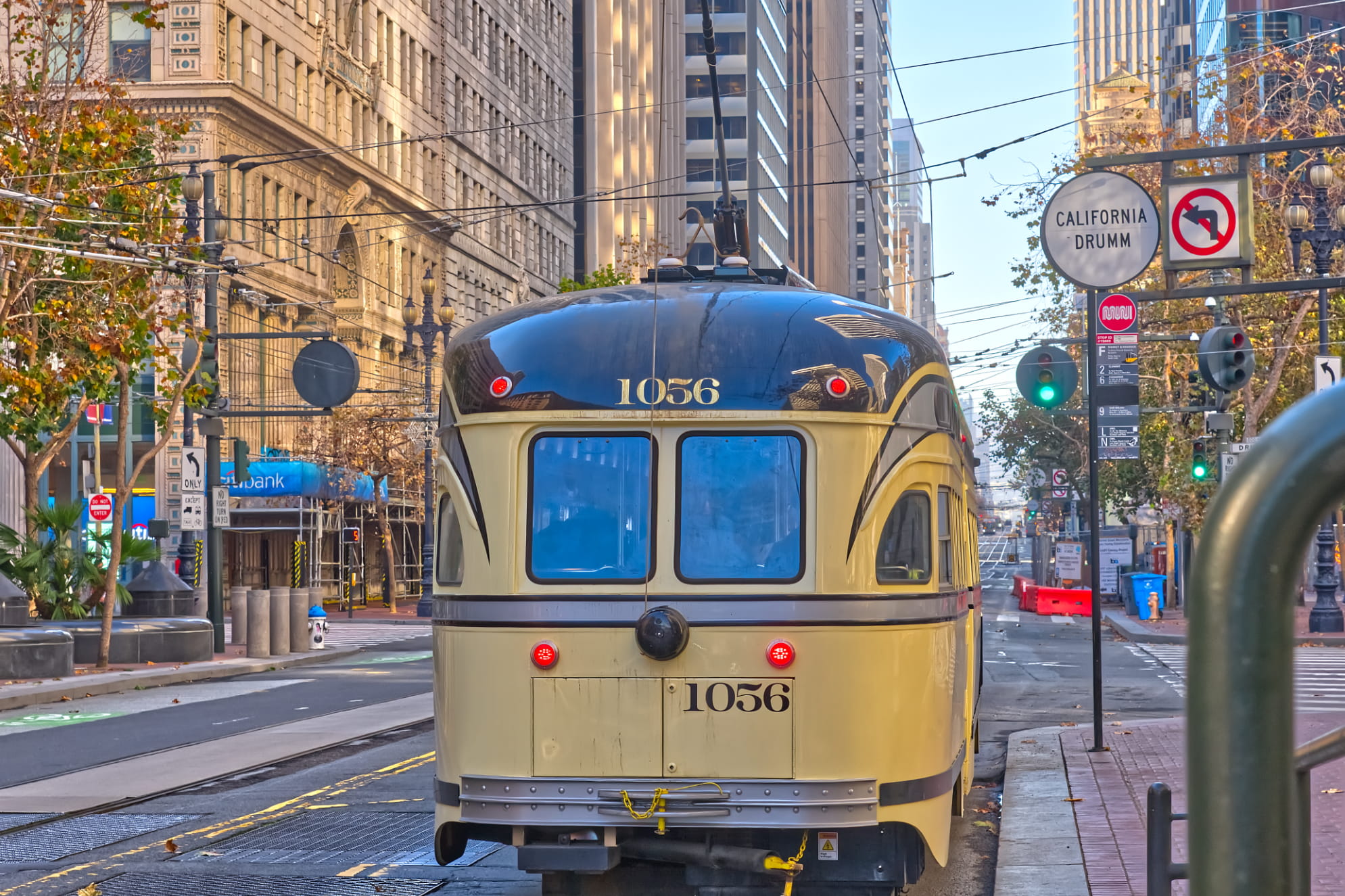 San Franciso trolley car sits curbside at California and Drumm in downtown. Busy street scene surrounds.