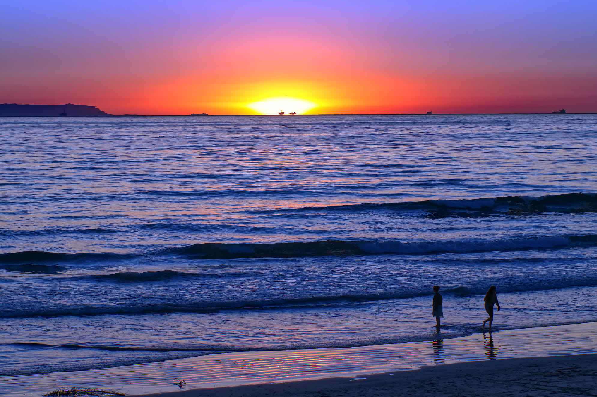 Radiant beach sunset with marble blue colored water and children playing on seashore. Photo from Venice Beach California.