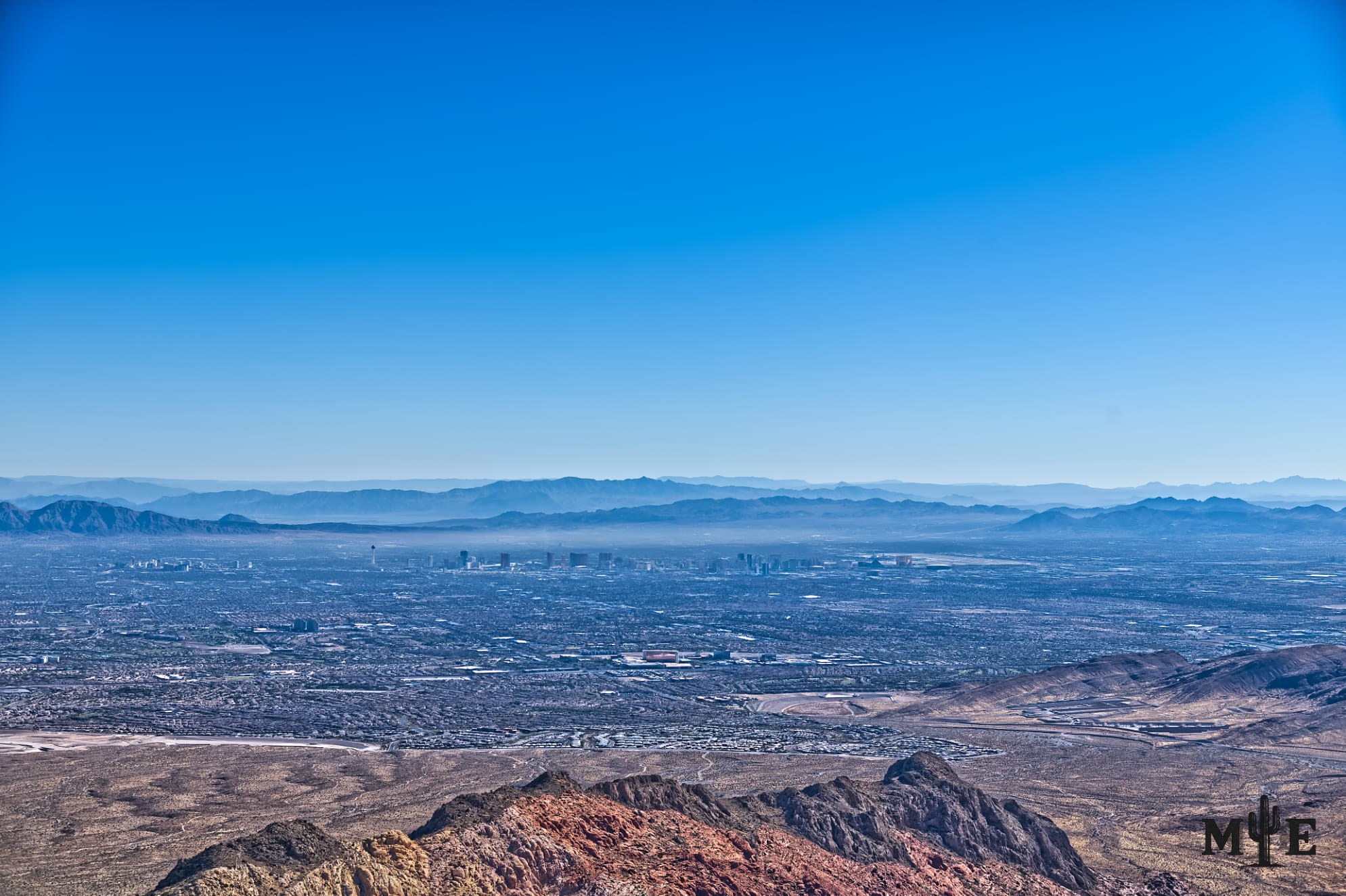 Wide angle shot of the Las Vegas valley with mountain peak ledge in center bottom. Captured on blue sunny day.