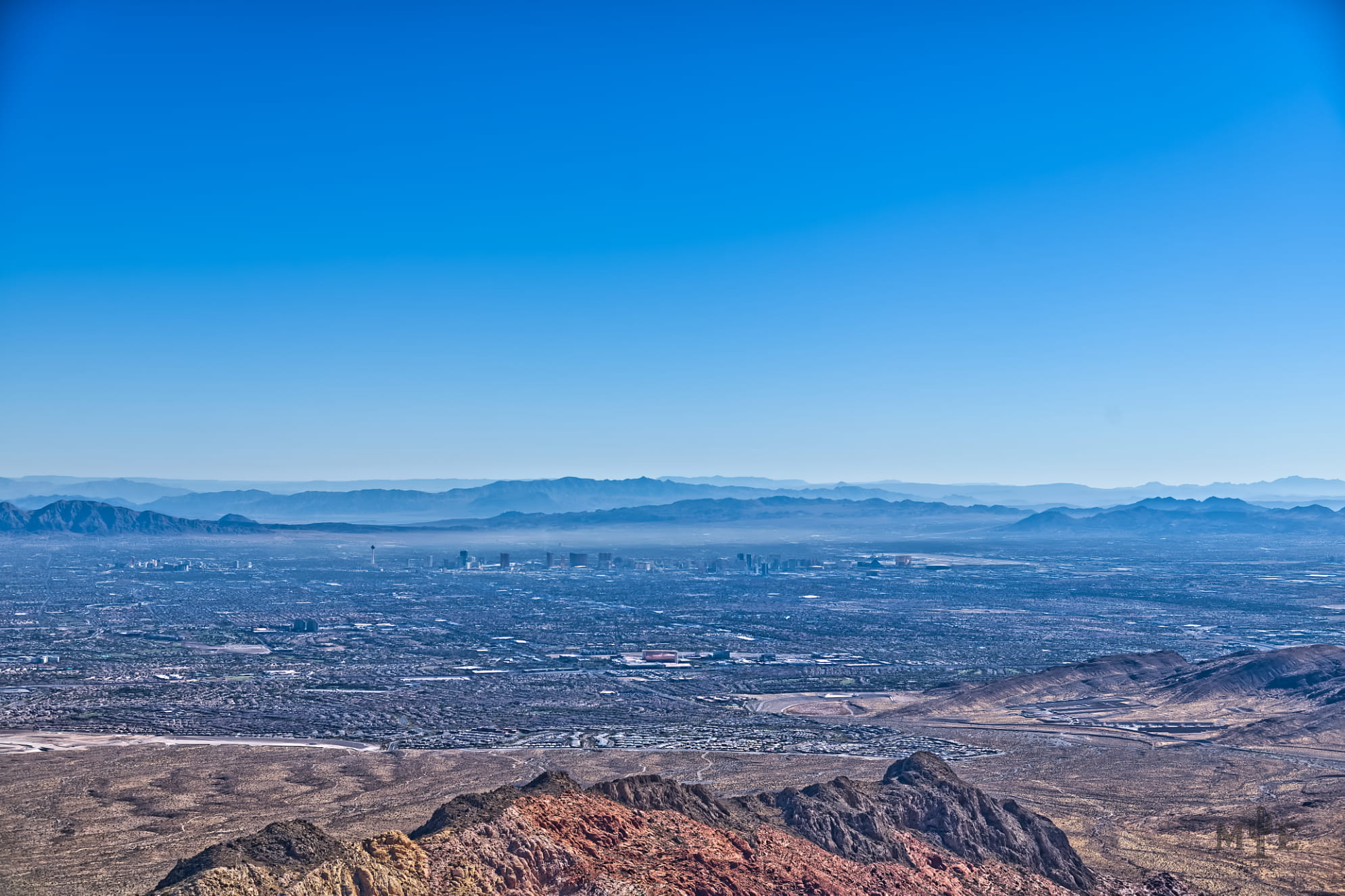Wide angle shot of the Las Vegas valley with mountain peak ledge in center bottom. Captured on blue sunny day.