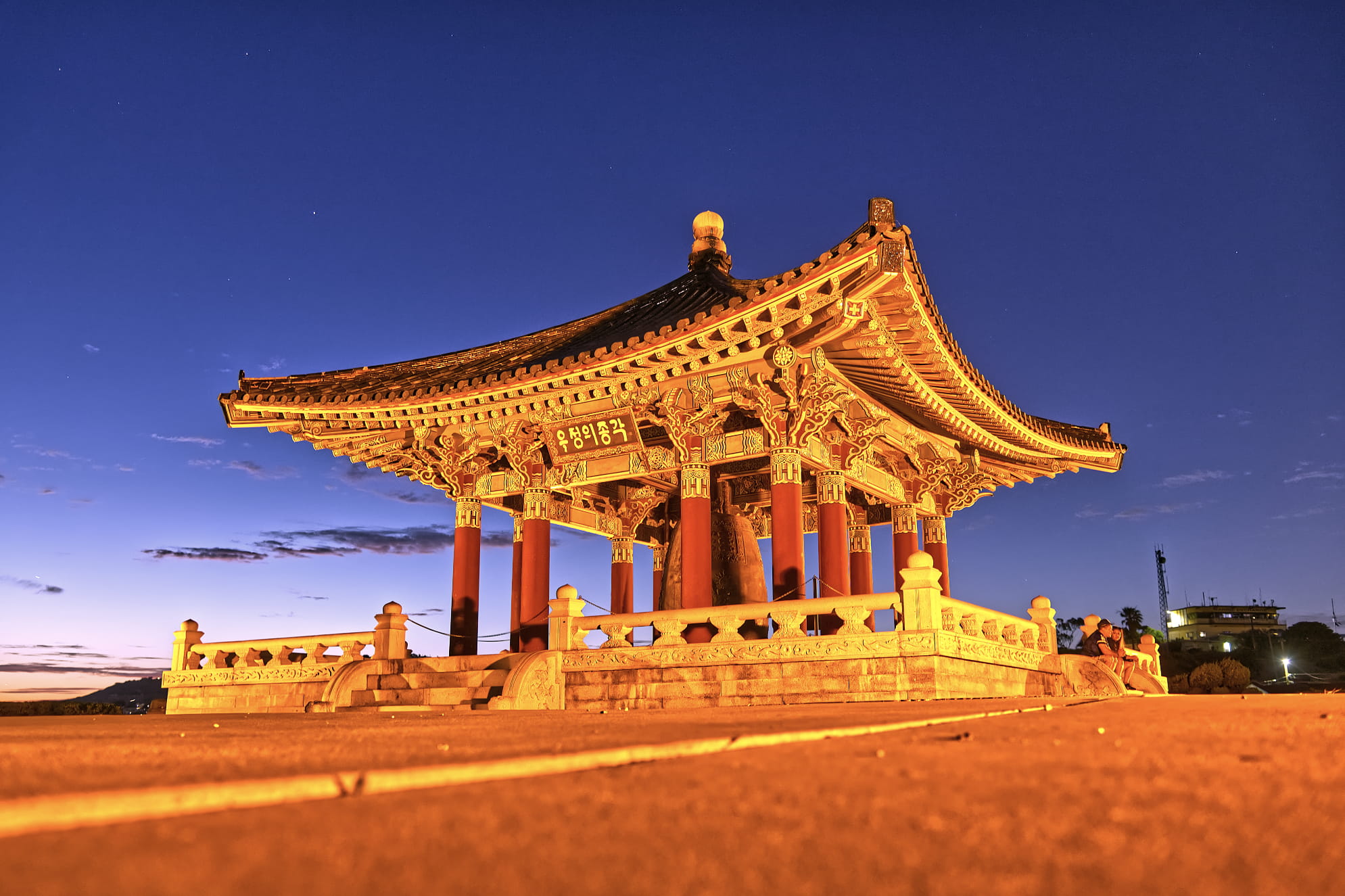 Korean Friendship Bell photograph with gradient night sky and bright orange gold colors on the structure and pavement.