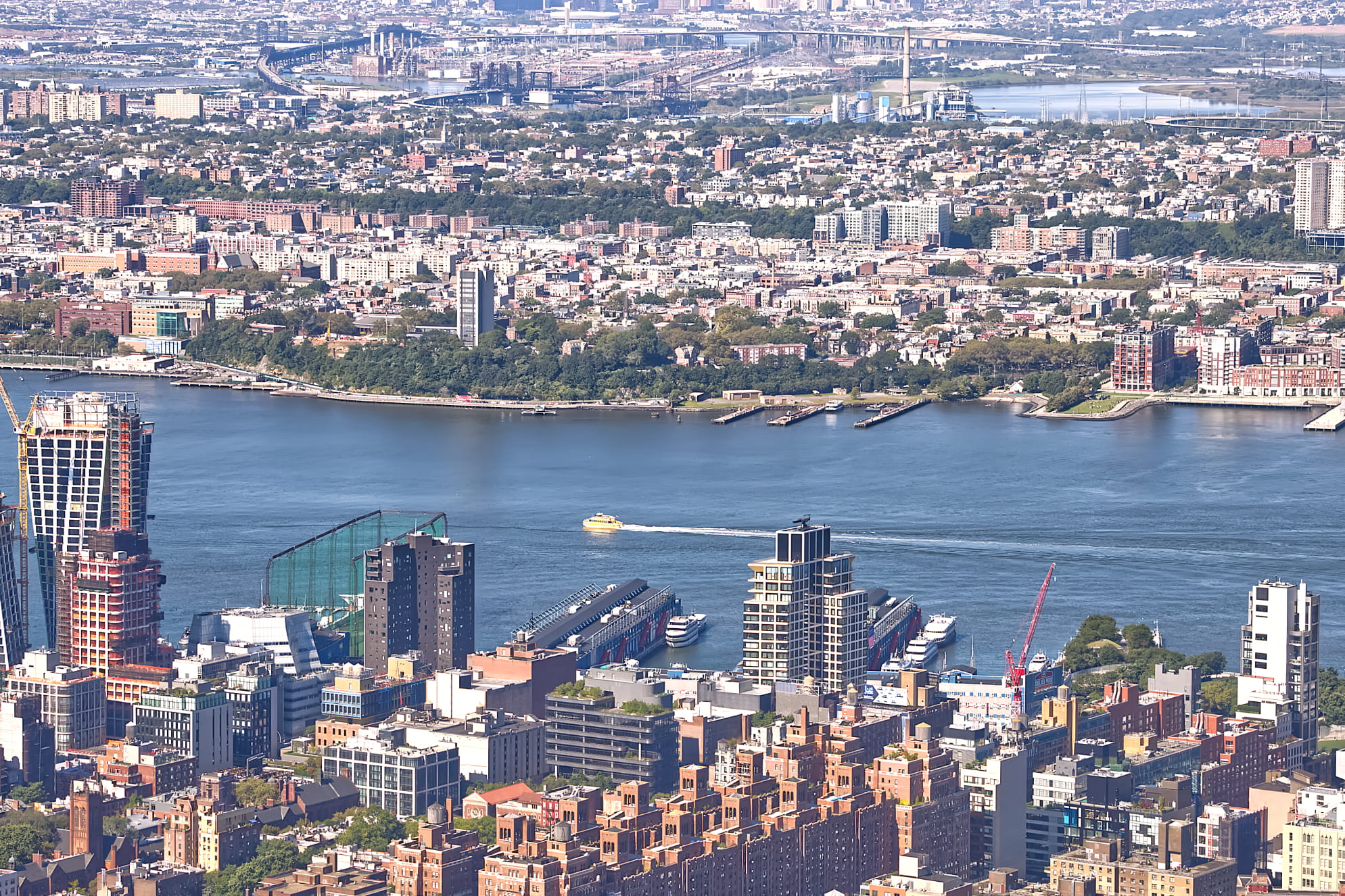 Yellow, small boat moving down the Hudson River in NYC with a detailed view of Manhattan. Metropolitan photograph.