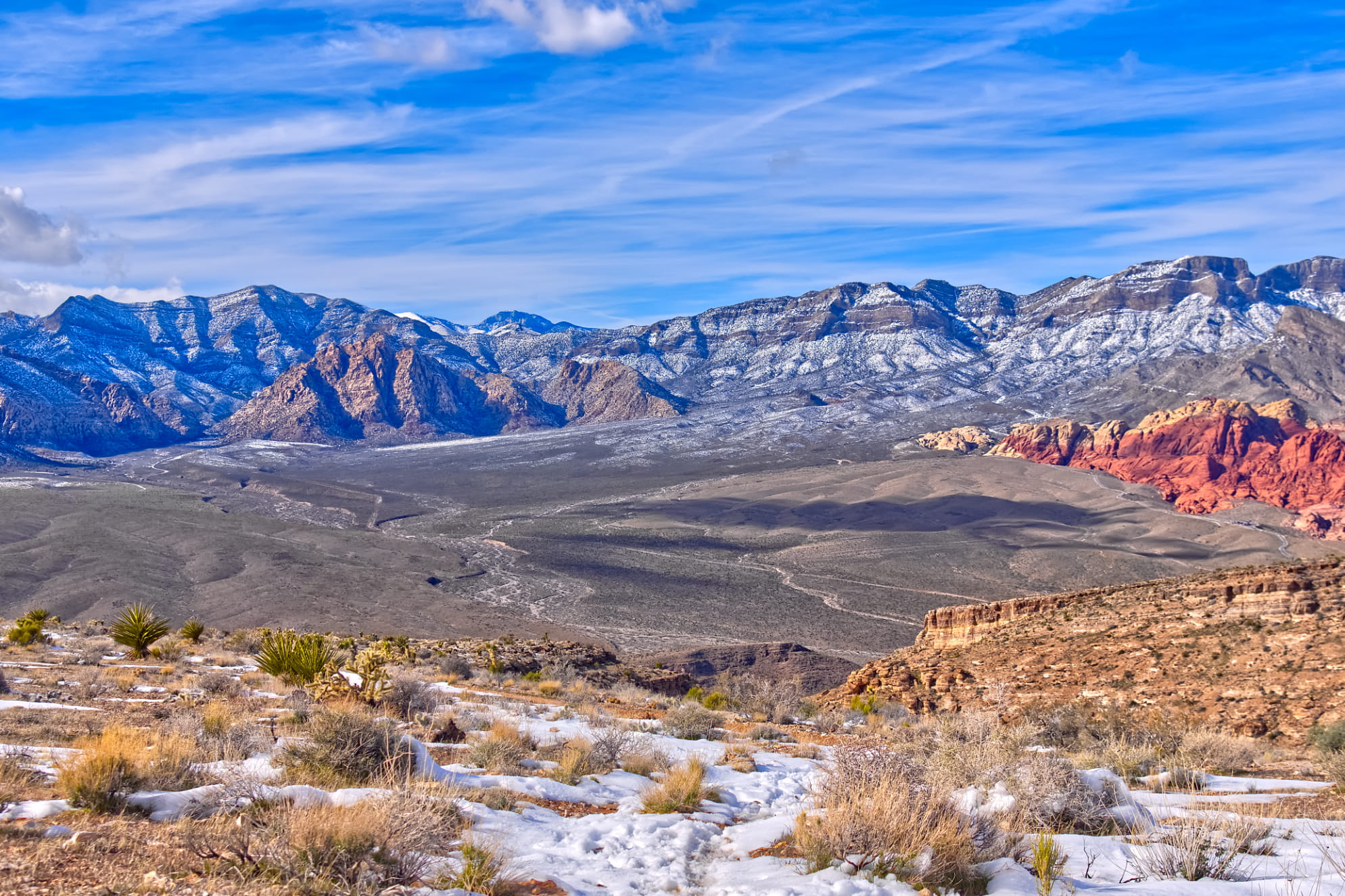 Vibrant blue sky over Spring Mountains lightly covered with snow on a cold day. Scattered snow in the foreground.