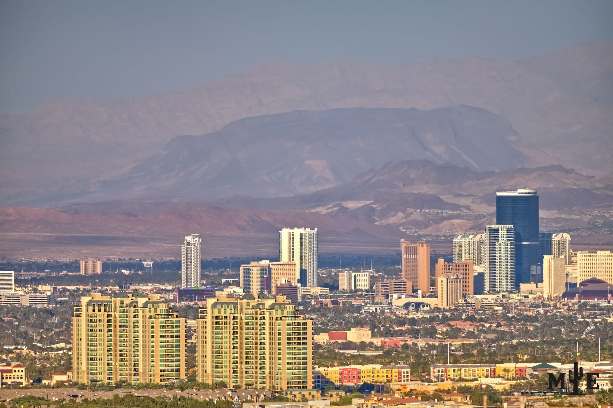 Luxury condominium towers in the foreground with part of the Las Vegas Strip rising across the valley in the distance.