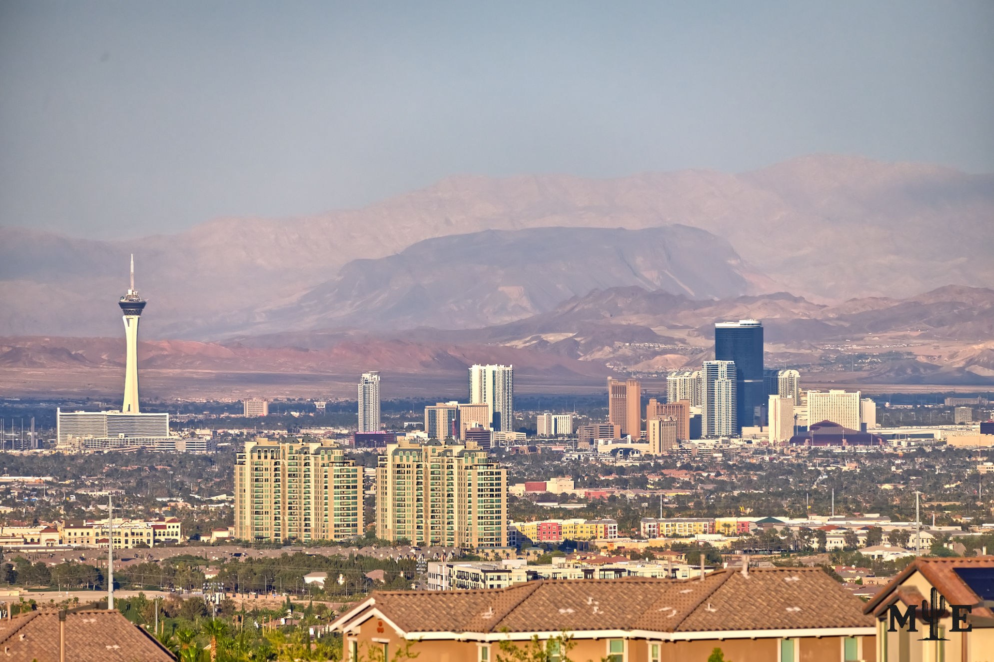 Residential rooftops and condominium towers leading toward the north Strip skyline, illustrating everyday life across Clark County.