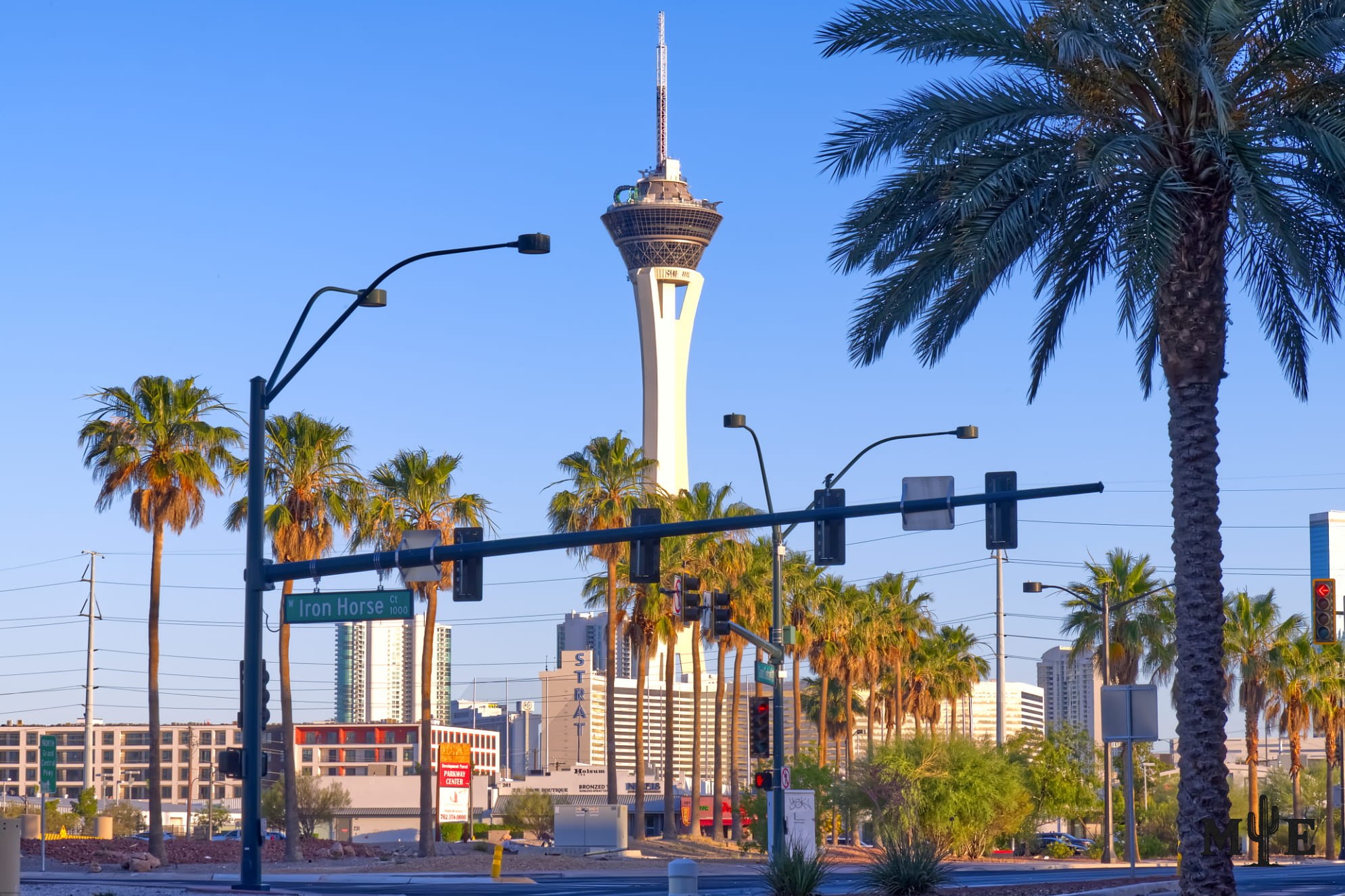 Quiet business district intersection with palm trees, shrouding the bottom portion of the Stratosphere.