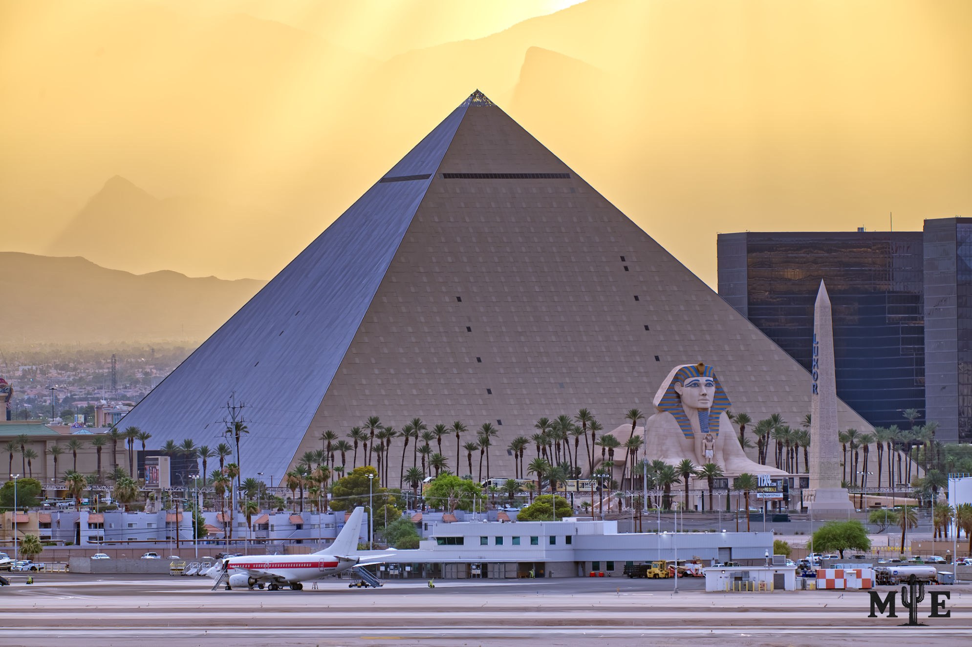 Golden sunset light and rays cover the Las Vegas mountains. Passenger jet sits idle on Harry Reid Airport runway.