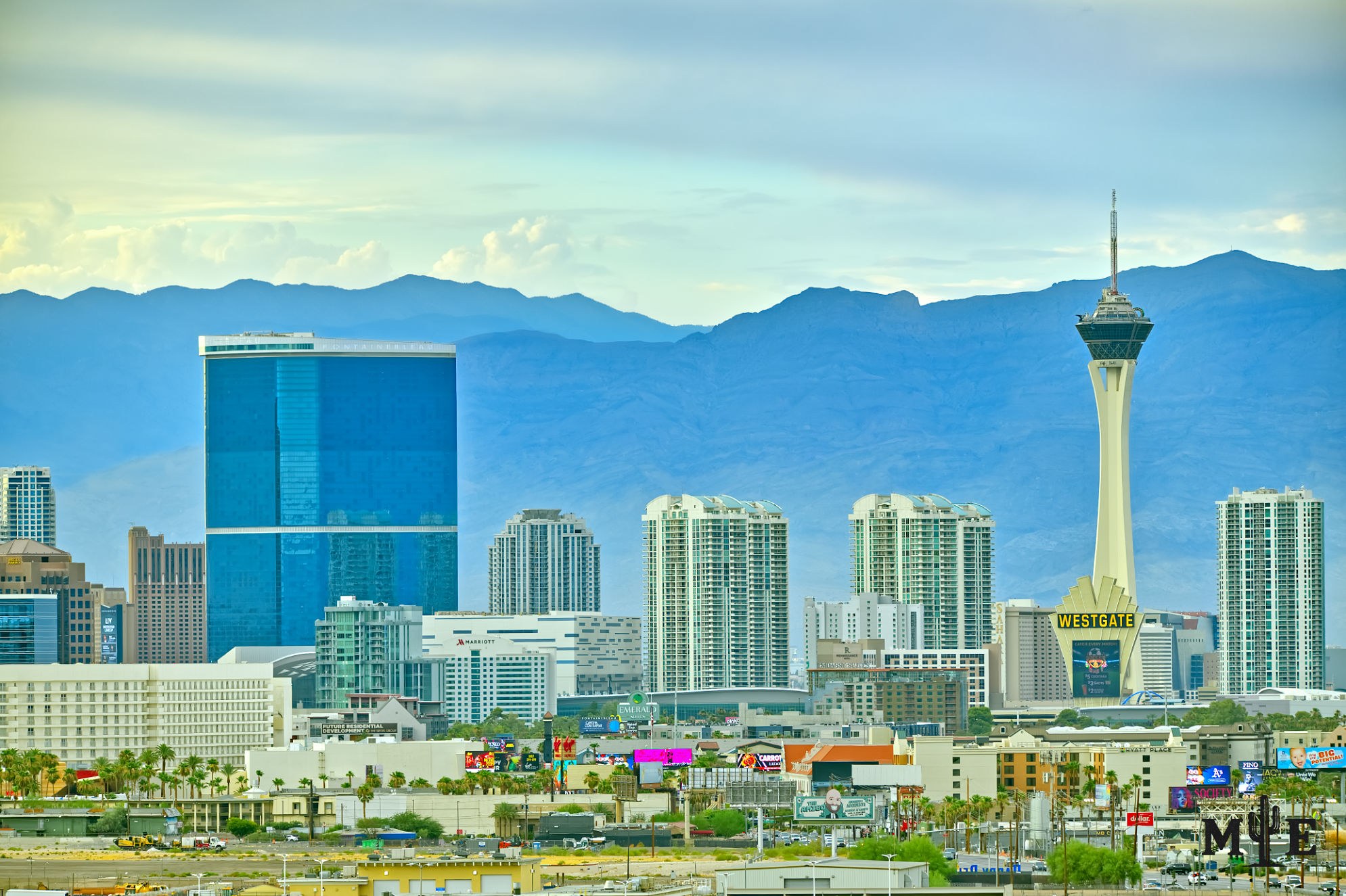 Fontainebleau Las Vegas rising above neighboring towers at dawn, with the Strat and Spring Mountains in the distance.