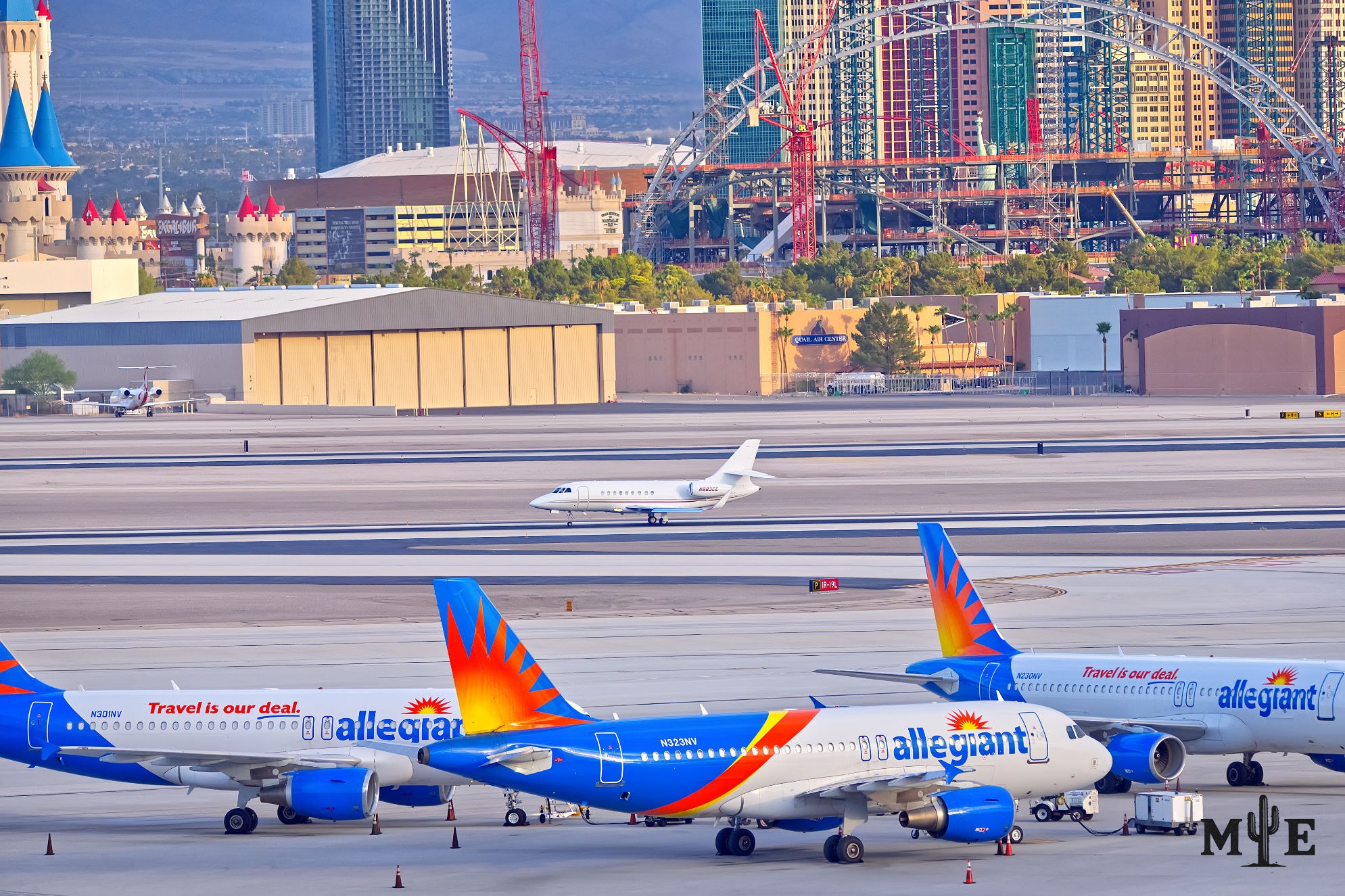 Three commercial jets aligned on a Las Vegas runway, with a smaller aircraft and faint Strip architecture in the distance.