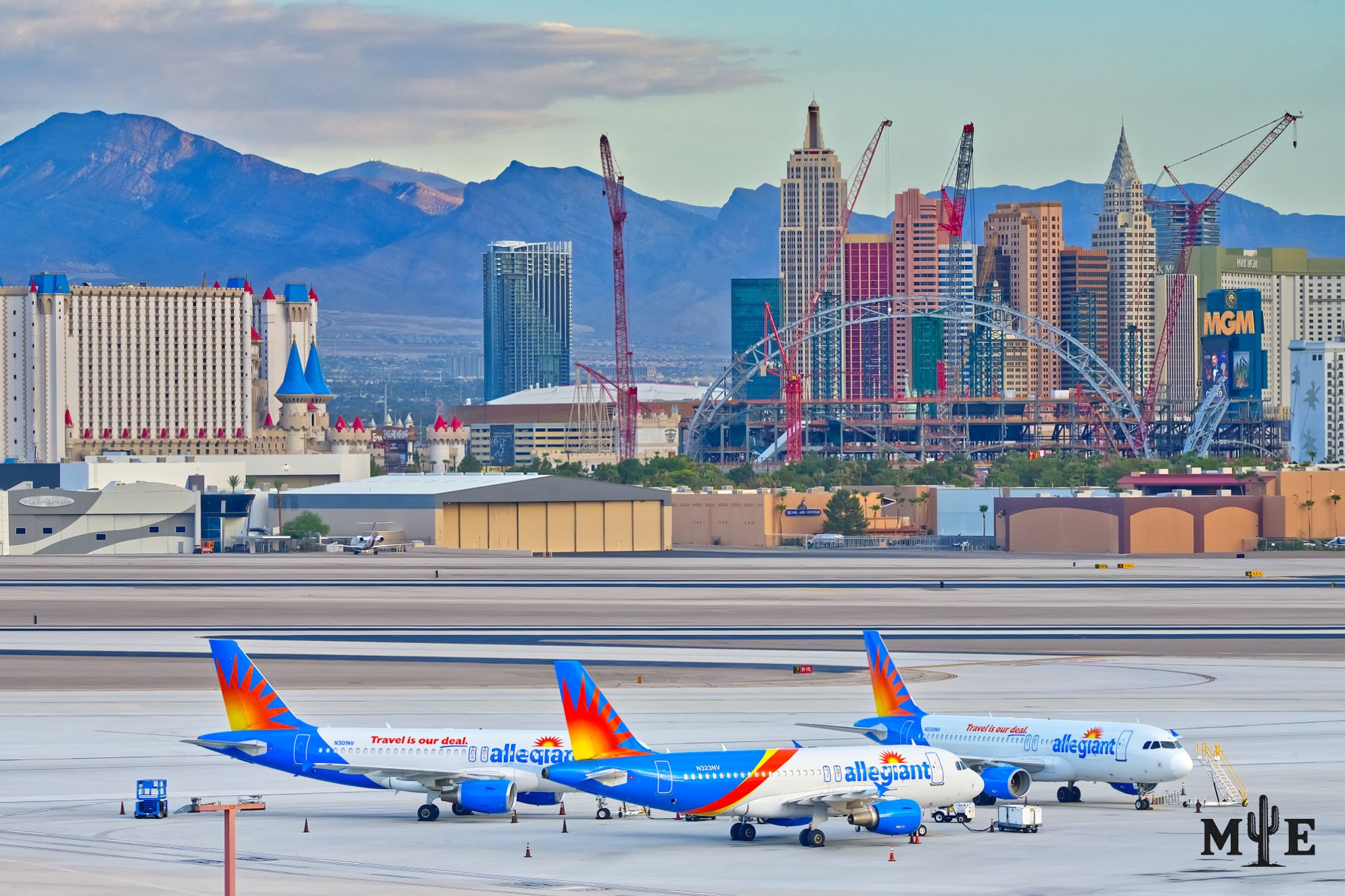 Airplane jets parked on the Harry Reid International Airport tarmac with Las Vegas Strip hotels and desert mountains in the background.